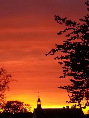 La silhouette d’un bâtiment surmonté d’une tour, se détachant sur un ciel au coucher du soleil.