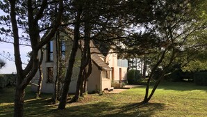 A house with a sloped roof, surrounded by a grassy yard and trees.
