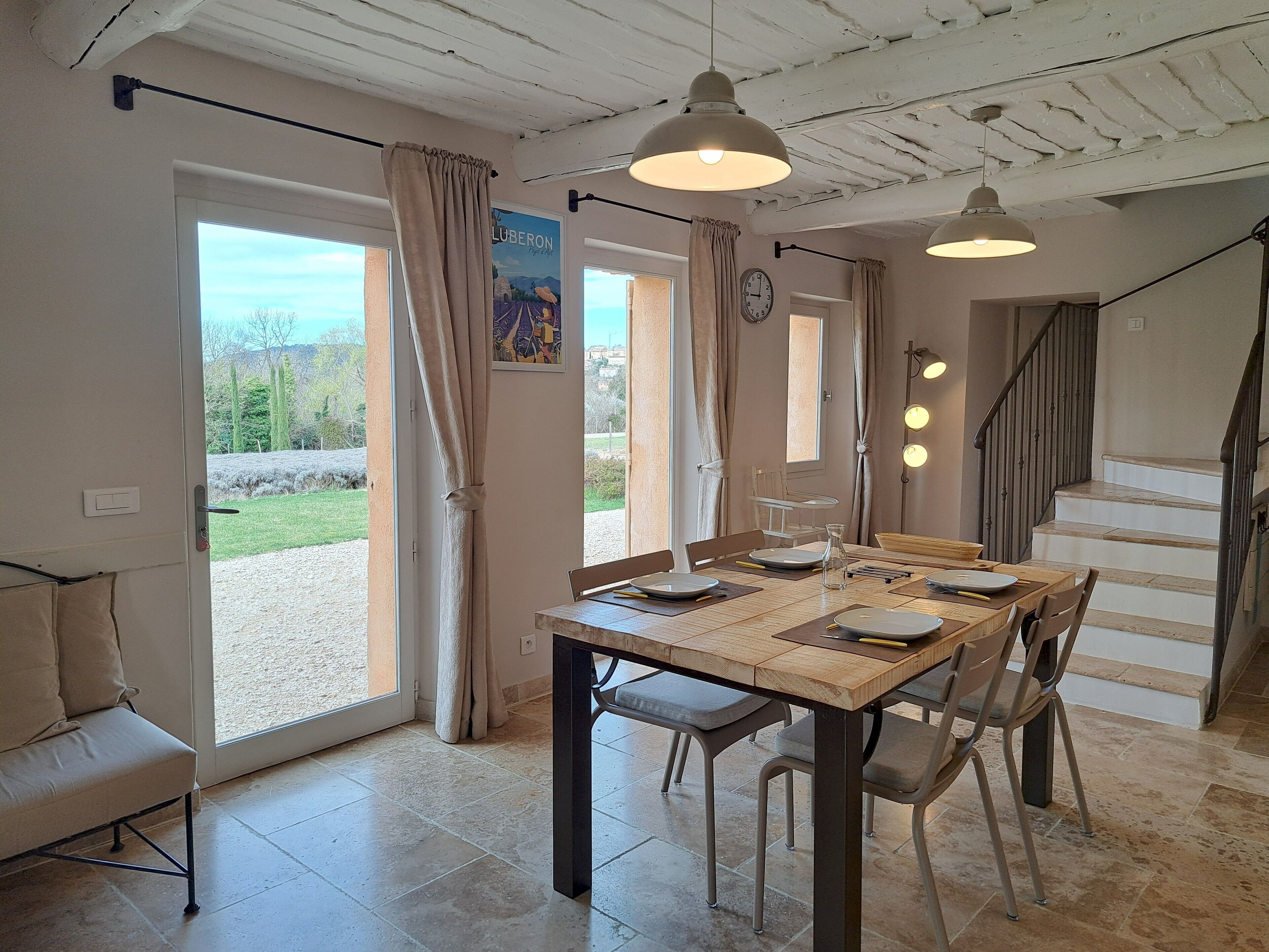 Een eetruimte met een tafel voor vier personen, een bank en een trap naar een hoger niveau.