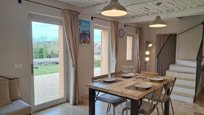 Een eetruimte met een tafel voor vier personen, een bank en een trap naar een hoger niveau.