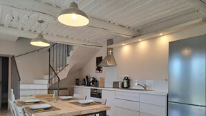 A modern kitchen with a dining area, stainless steel appliances, and a staircase leading to an upper level. - Bastidon with heated pool and private garden in the Luberon (Villars)