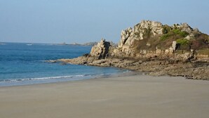 Ein Strand mit einer Felsformation und ruhiger See.