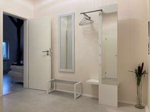 A modern bathroom with a white door, a mirror, a towel rack, a shelf, and a potted plant. - Apartment in the former farmhouse, with beams and lattice windows (Lübeck)
