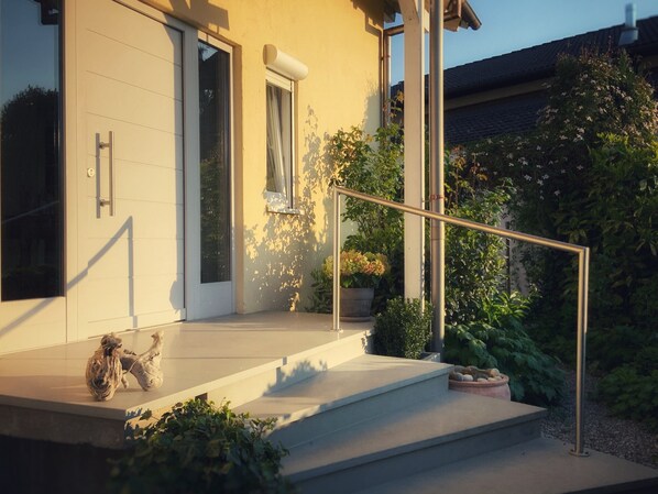A modern house with a concrete staircase, a metal handrail, and a door with a keyhole.