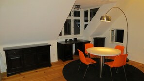 Cozy loft-style room with a dining area, desk, and sloped ceiling.