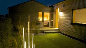 Une maison moderne avec une pelouse bien entretenue et un intérieur éclairé.