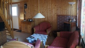 A cozy cabin interior with a wooden interior, a dining area with a table and chairs, and a fireplace.