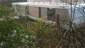 Un edificio moderno con techo plano, grandes ventanales y vista a un cuerpo de agua.