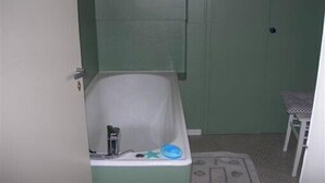 A bathroom with a bathtub, a small table, and a chair.