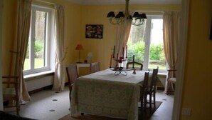 A dining area with a table set for four, a chandelier, and curtains on the windows.
