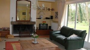 A living room with a fireplace, a green leather sofa, a wooden coffee table, and a large mirror.