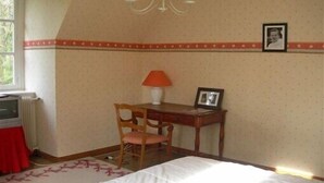 A bedroom with a bed, a desk, a chair, a lamp, and a radiator.