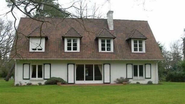A two-story house with a symmetrical facade, a central entrance, and a sloped roof.