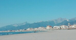 Uma praia com edifícios e montanhas ao fundo.