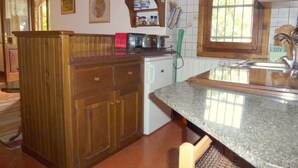 A kitchen with wooden cabinets, a granite countertop, and a window with a view of greenery. - Rustico in a panoramic position, terrace with sea view. (Pietrasanta)