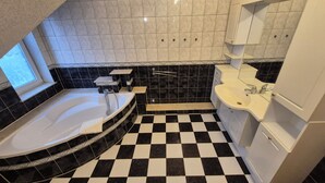 Une salle de bain avec un carrelage à motifs géométriques, une baignoire, un lavabo et un meuble-vasque avec des placards.