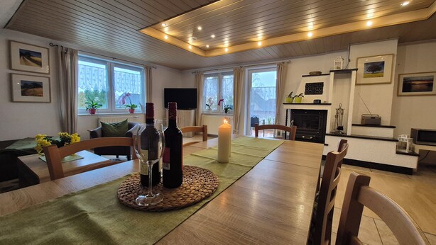Un salon chaleureux avec une table à manger en bois, des chaises, une cheminée et un téléviseur.