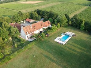 Una casa grande con piscina rodeada de exuberantes campos verdes.