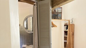 A bedroom with a bed, a wooden wardrobe, a mirror, and a bathroom with a sink and toilet. - Caseddu charming, small typical Corsican sheep (Sartène)