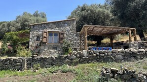 A stone building with a window and a wooden structure. - Caseddu charming, small typical Corsican sheep (Sartène)