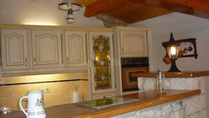 Una cocina con armarios de madera, encimera de piedra y una lámpara de estilo antiguo.