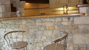 Una cocina con paredes de piedra, armarios de madera y dos taburetes de bar.
