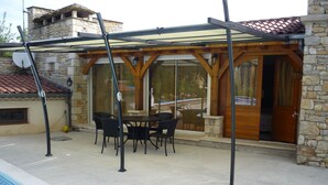 Un patio cubierto con mesa de billar, sillas, paredes de piedra y una puerta de madera.