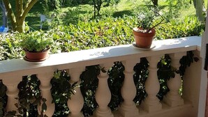 Un balcon doté d’une balustrade blanche, de plantes en pot et d’une table en marbre.