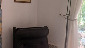 Une pièce avec une chaise noire, un lampadaire et deux tableaux encadrés accrochés au mur.
