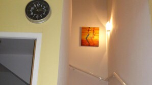 Eine Treppe mit beigen Fliesen, einer Wanduhr und einem Gemälde.