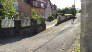 Eine Wohnstraße mit Häusern, einer gepflasterten Straße und einer Steinmauer mit Holzzaun.