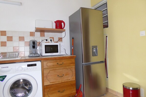 A compact kitchen with a washing machine, microwave, and a stainless steel refrigerator. - Between sea and mountain, near the beach and the volcano, (LE TAMPON)