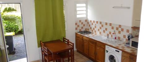 A compact kitchen with a dining area, a washing machine, and a small window.