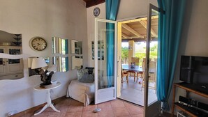 Une chambre avec un lit, une télévision, une table avec des chaises et une porte donnant sur un balcon.