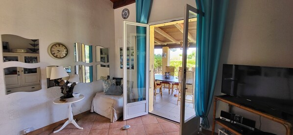 A room with a bed, a TV, a table with chairs, and a door leading to a balcony. - Mini villa by the sea (Poggio-Mezzana)