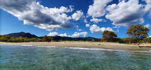 A beach with clear water, sandy shore, and mountains in the background. - Mini villa by the sea (Poggio-Mezzana)