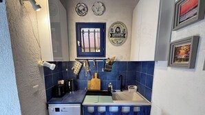Une cuisine de taille réduite, équipée d’un lave-vaisselle, d’un évier et de carreaux bleus.