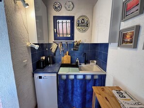 A compact kitchen with a dishwasher, sink, and blue tiles.