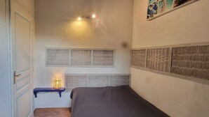 Une chambre à coucher avec un lit, une étagère avec une lampe et des panneaux décoratifs sur les murs.