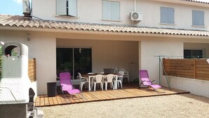 Une terrasse extérieure avec une table et des chaises, une plateforme en bois et un espace salon abrité.