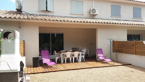An outdoor patio with a table and chairs, a wooden deck, and a covered seating area. - House with garden, calm, sea and view of the Ospédale massif (Sainte Lucie Porto Vecchio)