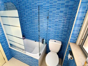 Une salle de bain avec une baignoire, des toilettes et un espace douche.