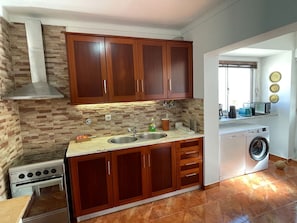 A kitchen with wooden cabinets, a double sink, a stove, and a washing machine.