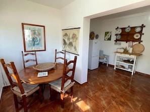 A dining area with a wooden table, chairs, and a framed picture. - Casa Matias - Charming Portuguese Beach House (Lourinhã)