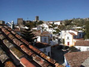 A historic town with white buildings, a prominent tower, and a fortified wall. - Matias Terrace House (Lourinhã)