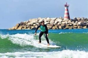 A person surfing with a lighthouse in the background. - Matias Terrace House (Lourinhã)