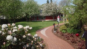 A garden pathway leading to a red building with a white fence. - Pleasant, modern and cozy, our apiary (Ulsnis)