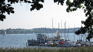 A marina with several boats docked, surrounded by greenery and a calm body of water. - Pleasant, modern and cozy, our apiary (Ulsnis)