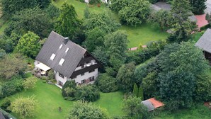An aerial view of a residential area with a house featuring a sloped roof, multiple windows, and a well-maintained lawn. - Pleasant, modern and cozy, our apiary (Ulsnis)