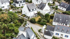 Ein Wohngebiet mit Häusern, einer schmalen Straße und einem kleinen Garten mit Tisch und Stühlen.